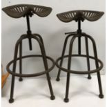 A pair of iron tractor seat stools, the seats inscribed "Wm Doyle & Co.