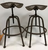 A pair of iron tractor seat stools, the seats inscribed "Wm Doyle & Co.