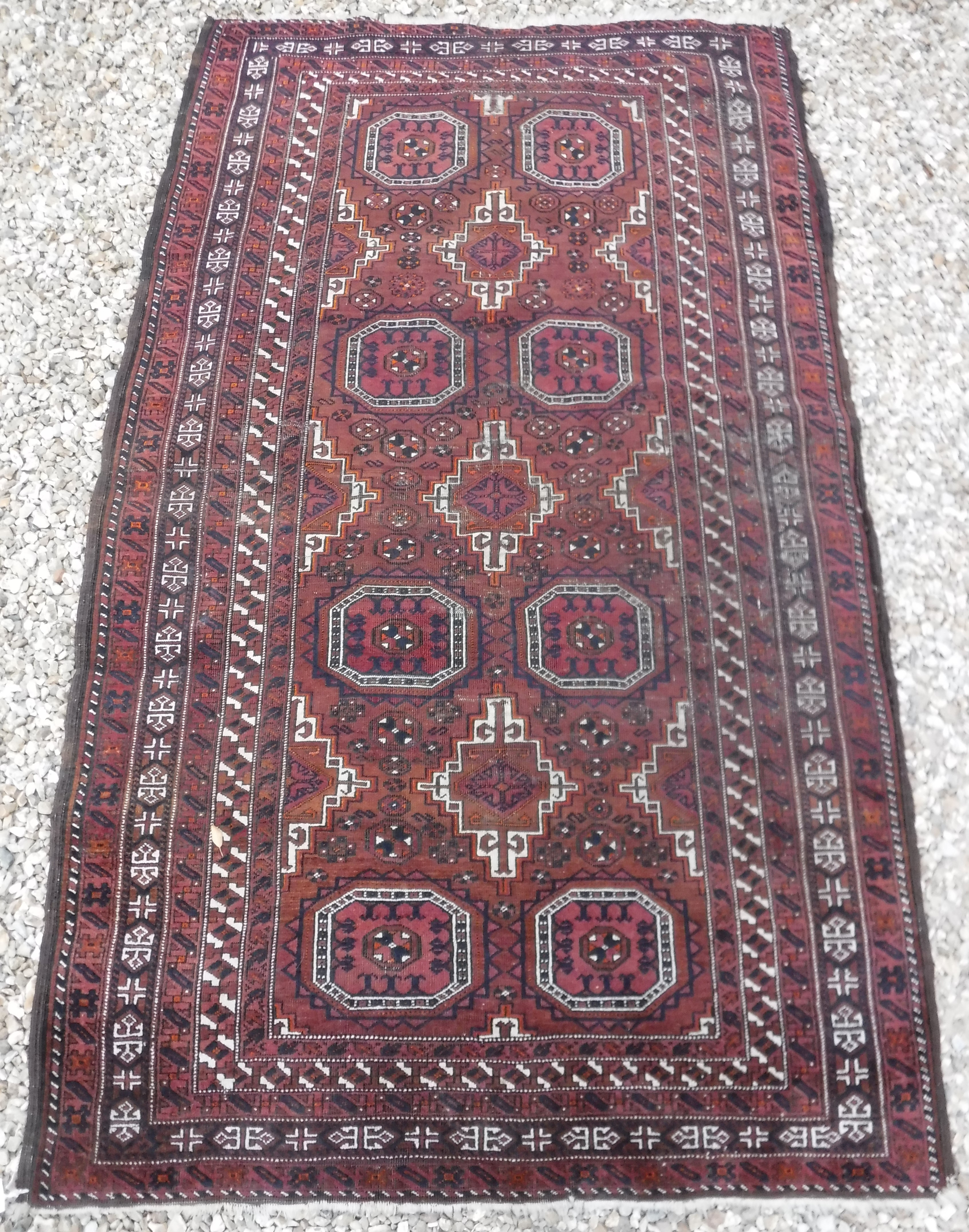 A Turkamen tribal rug with repeating elephant foot medallions on a plum ground,