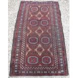 A Turkamen tribal rug with repeating elephant foot medallions on a plum ground,