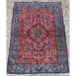 A Persian rug with centre medallion on a floral and foliate decorated red ground,