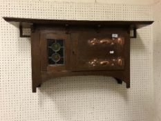An oak, leaded glazed and copper embellished wall cabinet in the manner of Liberty of London,