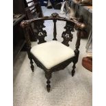 A Victorian carved walnut yoke back corner chair in the 18th Century manner with cherubim and lion