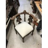 A Victorian carved walnut framed yoke back corner chair with cherubim and foliate carved decoration