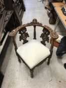 A Victorian carved walnut framed yoke back corner chair with cherubim and foliate carved decoration
