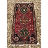 A Persian rug with repeating lozenge medallions on a green and blue ground,