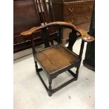 An 18th Century oak yoke back corner chair with plank seat on turned legs united by stretchers,