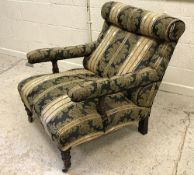 A stained beech framed and upholstered open arm easy chair on carved and turned supports in the