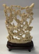 An early 20th Century carved ivory ornament depicting figures in landscape on stand,