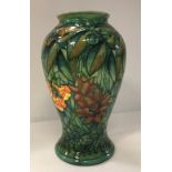 A Moorcroft rainforest baluster shaped vase with floral decoration on a green ground signed to base