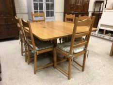 A modern oak dining table raised on twin pedestal supports united by an H stretcher,