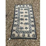 A Chinese rug, the central panel set with repeating Oriental floral motifs on a cream ground,
