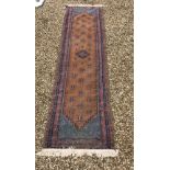A Persian runner, the central panel set with repeating motifs on a dark brown ground,