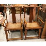 A pair of 20th Century Chinese elm elbow chairs with rattan seats on turned legs united by