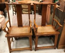 A pair of 20th Century Chinese elm elbow chairs with rattan seats on turned legs united by