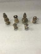 A collection of silver peppers, to include two baluster-shaped peppers,