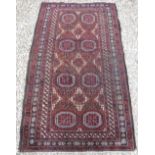 A Turkamen tribal rug with repeating elephant foot medallions on a plum ground,