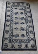 A Chinese rug, the central panel set with repeating Oriental floral motifs on a cream ground,