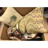 A box of assorted scatter cushions and two large circular table cloths
