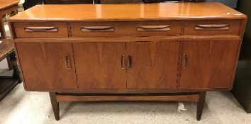 A 1970's Gomme "G-Plan" teak sideboard, the plain top above three drawers and four cupboard doors,