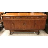 A 1970's Gomme "G-Plan" teak sideboard, the plain top above three drawers and four cupboard doors,