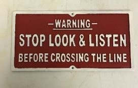 A modern painted cast metal sign "Warning Stop Look and Listen Before Crossing the Line",