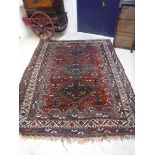 A Shiraz tribal carpet with three repeating lozenge medallions on a red ground with all over bird