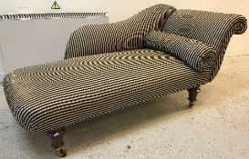 A Victorian upholstered scroll end chaise longue on turned legs to brass caps and castors