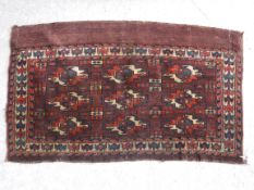 A Bokhara Juval rug with repeating medallion decoration on a plum ground,