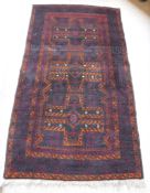 A Turkaman rug with three repeating cross medallions in terracotta on a deep wine ground,