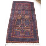 A Turkaman rug with three repeating cross medallions in terracotta on a deep wine ground,