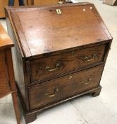 An 18th Century elm bureau the sloping fall enclosing a basic fitted interior over two drawers with