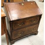 An 18th Century elm bureau the sloping fall enclosing a basic fitted interior over two drawers with