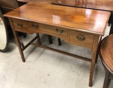 An Edwardian mahogany three drawer side table on square tapered legs united by stretchers,