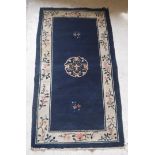 A circa 1950 Chinese rug, the central panel set with floral decorated medallion on a blue ground,