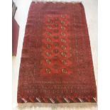 A Turkamen rug with repeating elephant foot medallions on a red ground,