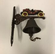 A modern painted cast metal wall bell with vintage car decoration