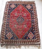 A Shiraz rug with lozenge shaped medallion on a red ground with all over geometric floral design,