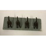 A set of four modern cast metal mounted dog tail hooks on slate base,