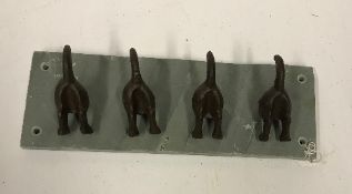 A set of four modern cast metal mounted dog tail hooks on slate base,