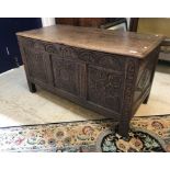 A 17th Century oak coffer, the later top over a lunette carved frieze and three carved panels,