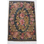 An English needlework rug with centre medallion of floral spray within a floral wreath border,