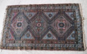 A Caucasian rug with three repeating lozenge shaped medallions on a pale blue ground,