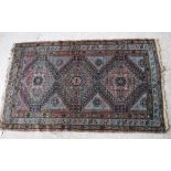 A Caucasian rug with three repeating lozenge shaped medallions on a pale blue ground,