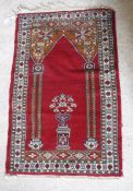 A Bokhara rug the central panel set with Mirhab style design on a red ground within a stepped red,