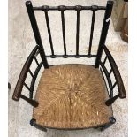 A circa 1900 ebonised beech framed Sussex type armchair after a design by William Morris with rush
