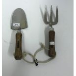 A stainless steel wooden handled hand trowel and fork