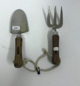 A stainless steel wooden handled hand trowel and fork