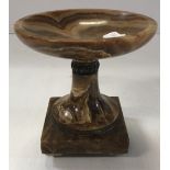 A brown onyx urn with silvered metal embellishments/banding on tapered feet,