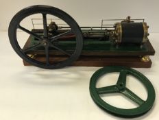 A bespoke stationary steam engine with green painted base and over-sized black painted fly wheel